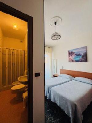 a bedroom with two beds and a bathroom with a sink at Pensione Aurora in Imperia