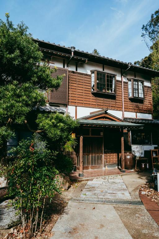 a house with a gate and a tree at ゲストハウス nagatafure in Iki