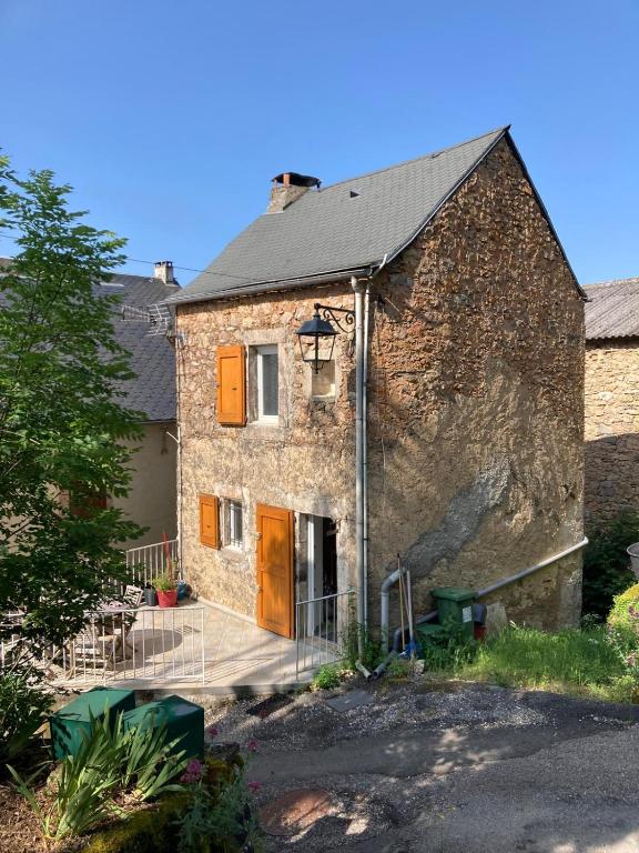 an old stone house with a porch and a driveway at La Modestine in Lanuéjols
