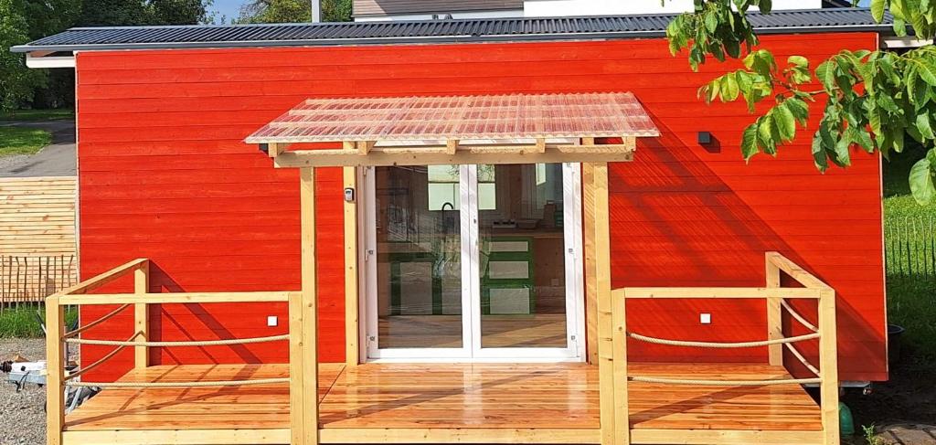 a red building with a deck with a red house at Tiny House Reichle in Boms