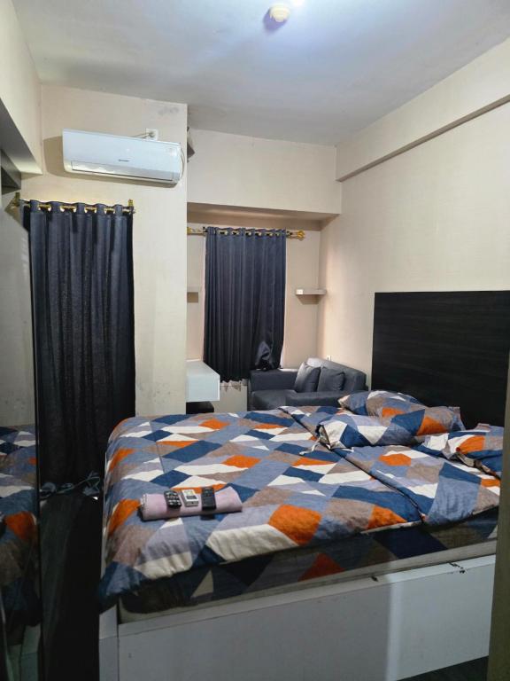 a bedroom with a bed with a colorful comforter at Apartemen Mahogany By Ruang Sultan in Karawang