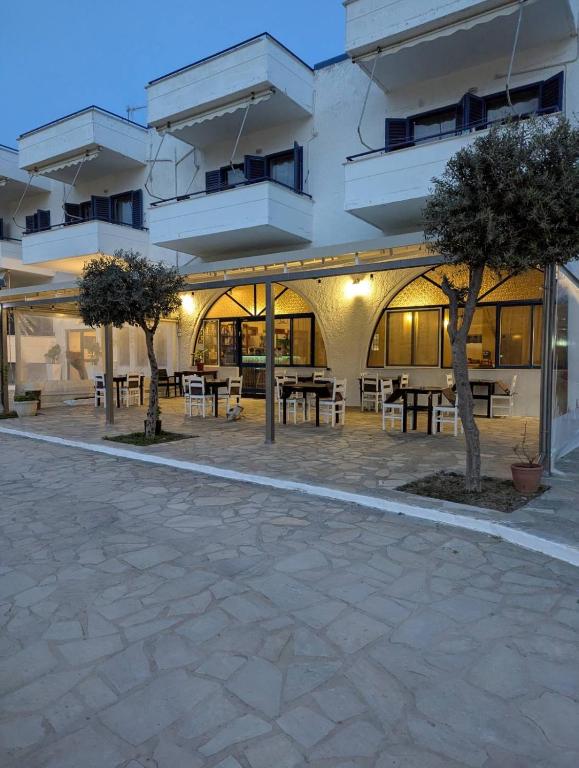 a building with tables and trees in a courtyard at To Kyma in Amarynthos