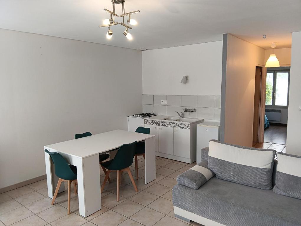 a kitchen and living room with a table and a couch at Appartement rez-de-chaussée calme in Neuilly-lʼÉvêque