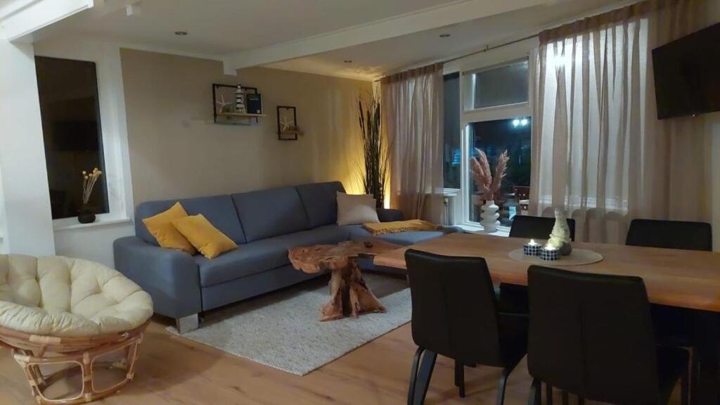 a living room with a blue couch and a table at Ferienwohnung Nordholland in Nieuwe-Niedorp