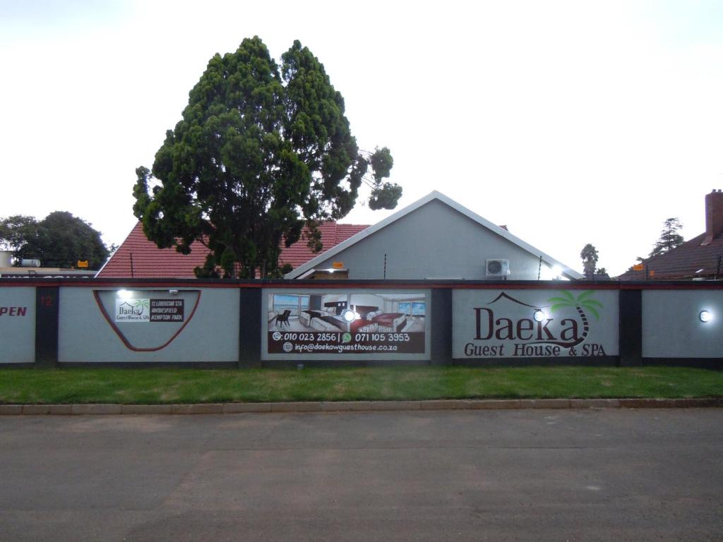 a white building with a tree in front of it at Daeka Guesthouse in Kempton Park