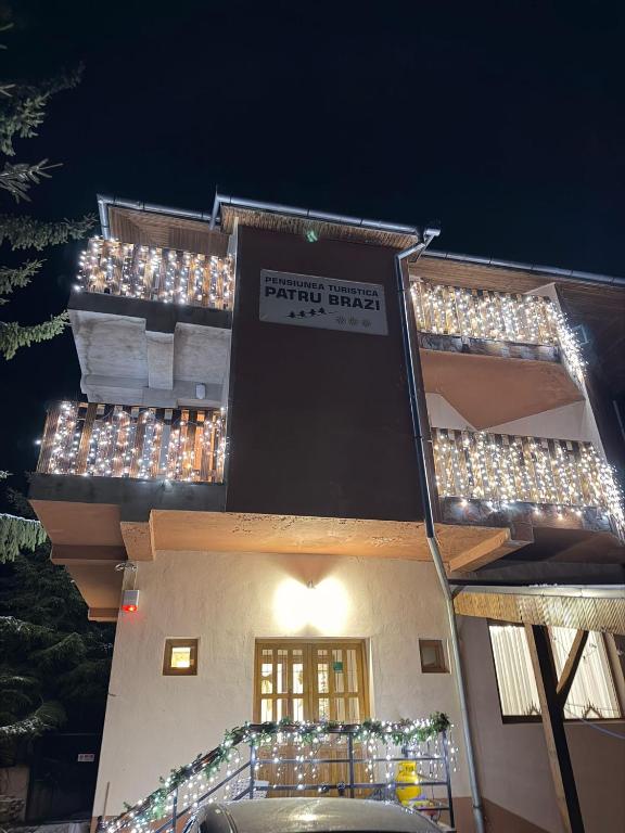 a building with christmas lights on the side of it at Pensiunea Patru Brazi in Muntele Cacovei