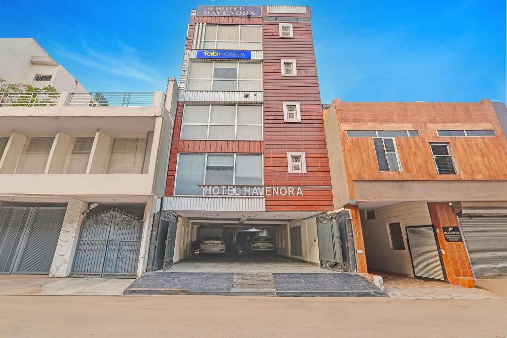 a tall building with a parking garage in front of it at FabHotel Havenora - Nr Maharani Bagh in New Delhi