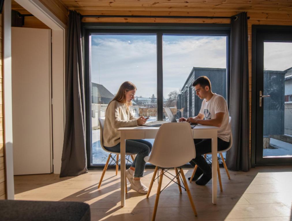 two people sitting at a table in a room with a window at Pixel - Tiny Campus in Târgu Secuiesc