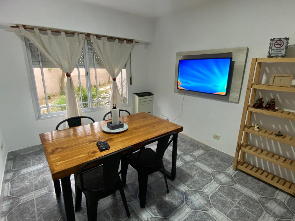 a dining room with a wooden table and a tv at Duplex 4 con cochera privada y parrilla in San Clemente del Tuyú