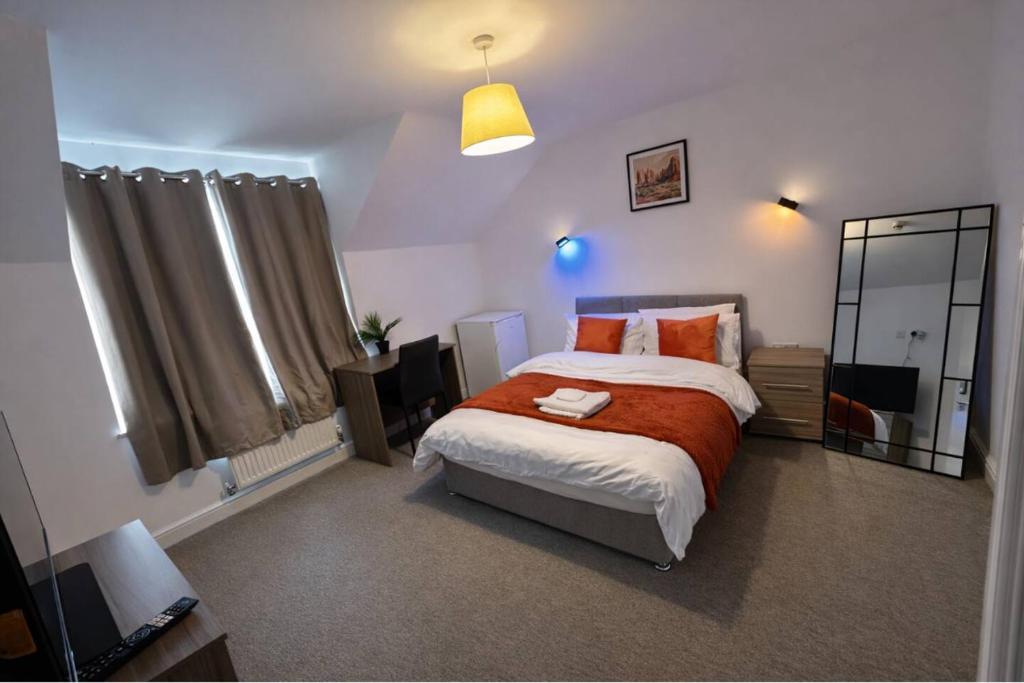a bedroom with a large bed and a mirror at Queens Court Ensuite Studio in Stoke on Trent
