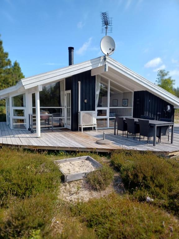 a house with a wooden deck with a table at Beautiful cottage on a large natural plot in Ålbæk