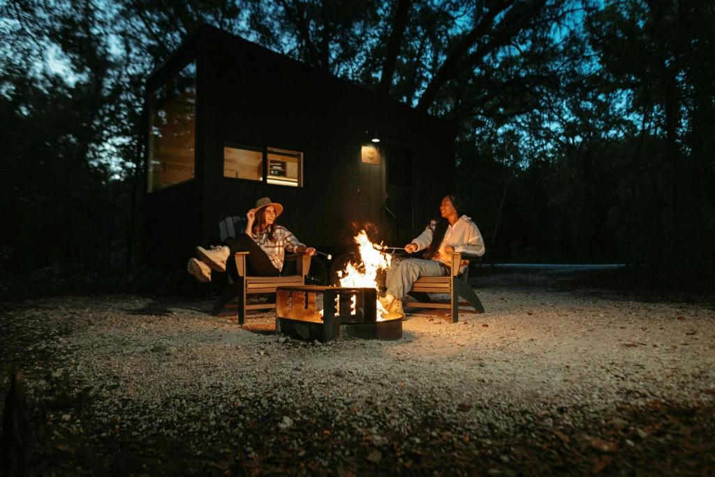 a group of people sitting around a fire at night at Postcard Cabins Piney Woods, Outdoor Collection by Marriott Bonvoy in Coffee City