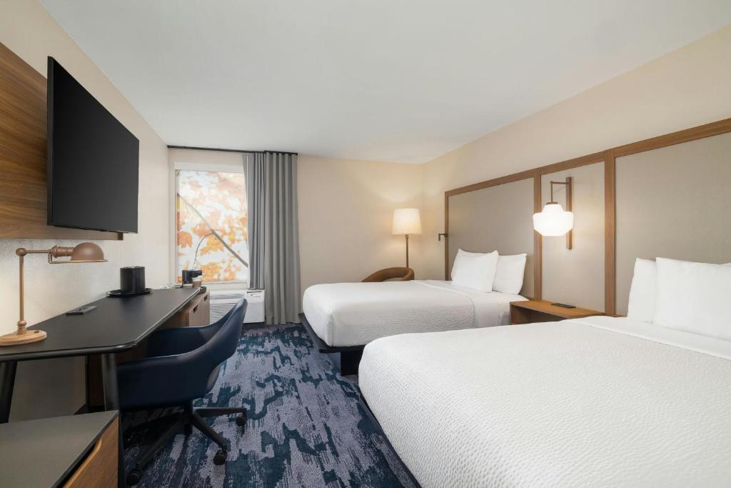 a hotel room with two beds and a desk at Fairfield by Marriott Inn & Suites Clinton in Clinton