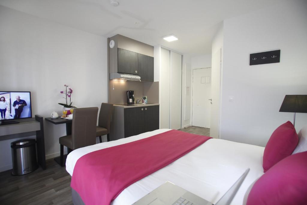 a bedroom with a bed and a desk and a kitchen at Odalys City Paris Levallois in Levallois-Perret