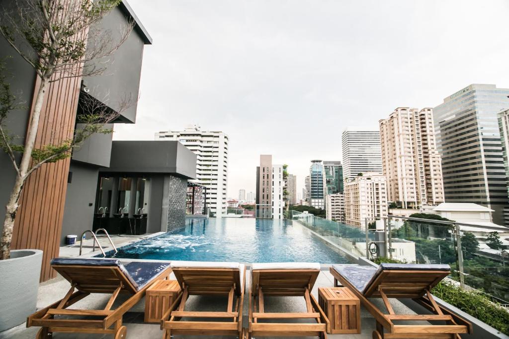 曼谷的住宿－Arte Hotel - SHA Extra Plus，一座带椅子的建筑屋顶上的游泳池