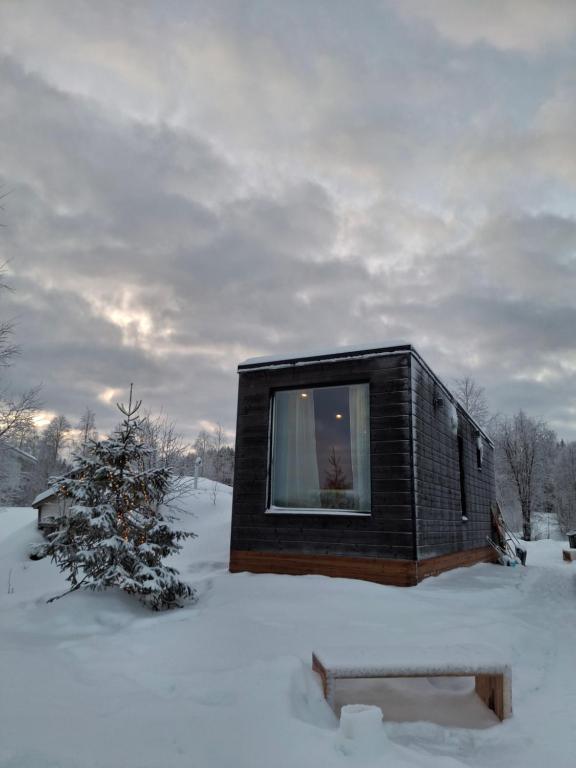 a small house in the snow with a tree at Arctic River View in Rovaniemi