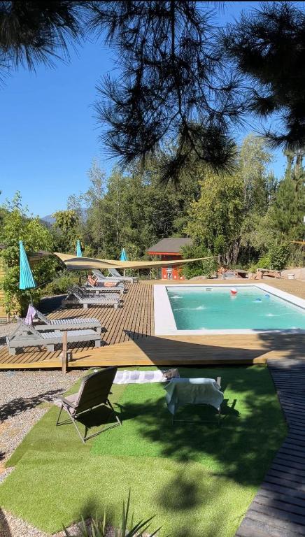 a swimming pool with a table and chairs in a yard at Cabañas Alto Quillay, radal siete tasas in El Torreón
