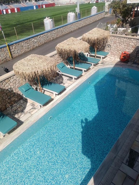 an overhead view of a swimming pool with chairs and straw umbrellas at Ifestia Hotel in Kamari