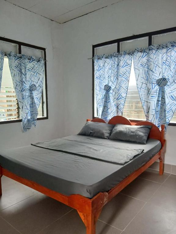 a bed in a room with two windows at Villa Rosita - Apo Island in Dauin