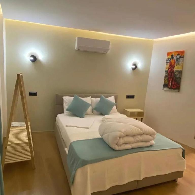 a bedroom with a bed with white sheets and blue pillows at Sığacıksenkonukevi in Siğacık