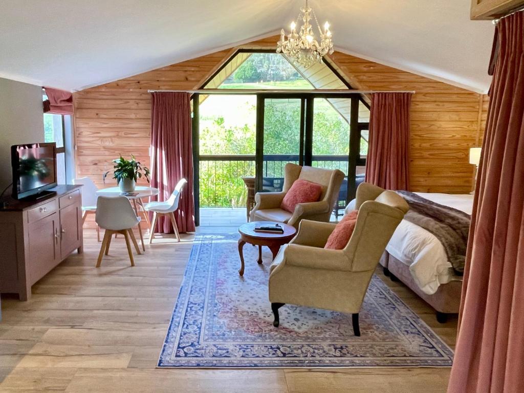 a bedroom with a bed and chairs and a tv at Heuwelsig Farm Cottages in Franschhoek
