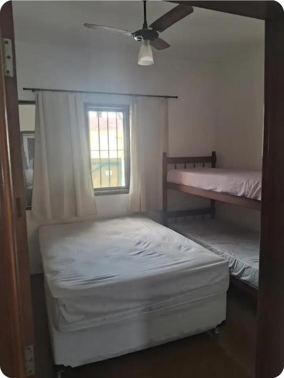 a bedroom with two beds and a ceiling fan at Quartos para locação in Mongaguá