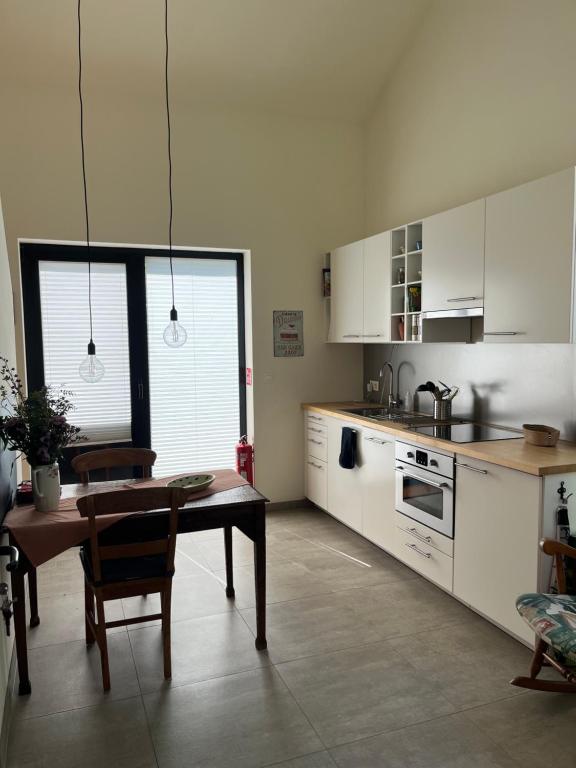 a kitchen with white cabinets and a table in it at Bellefleur Cottage in Herent