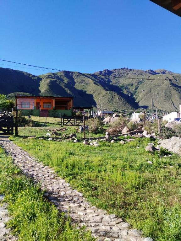 a cobble stone road leading to a house in the mountains at Habitaciones La Apacheta - El Mollar in Tafí del Valle