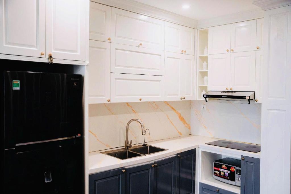 a white kitchen with a sink and a black refrigerator at Home MinMimi in Gia Lâm Pho