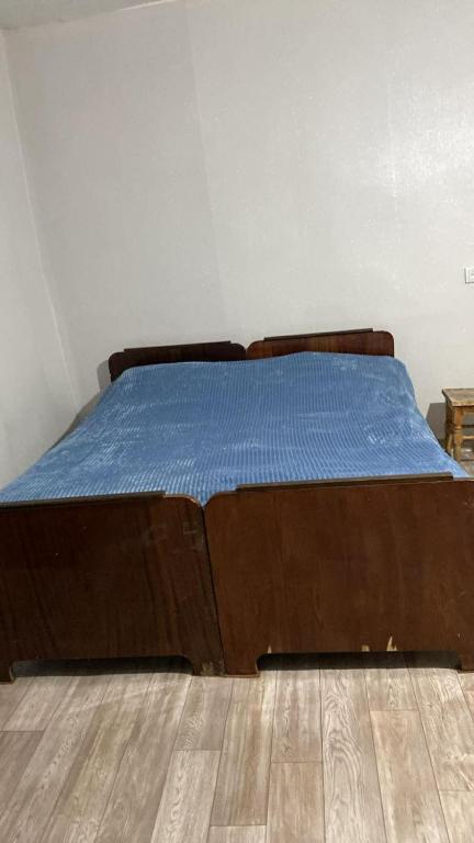 a bed with a blue comforter on a wooden floor at Old Guesthouse Tsikhisdziri in Tsikhisdziri