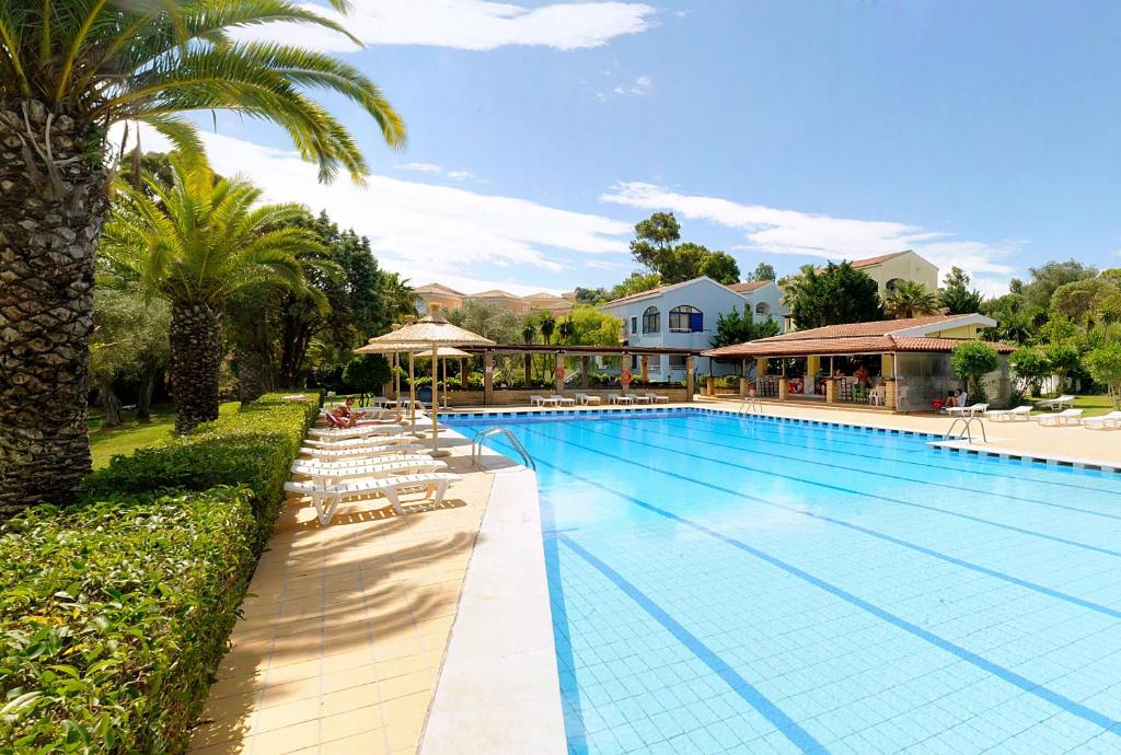 una grande piscina con sedie e ombrelloni di Helion Resort a Gouviá