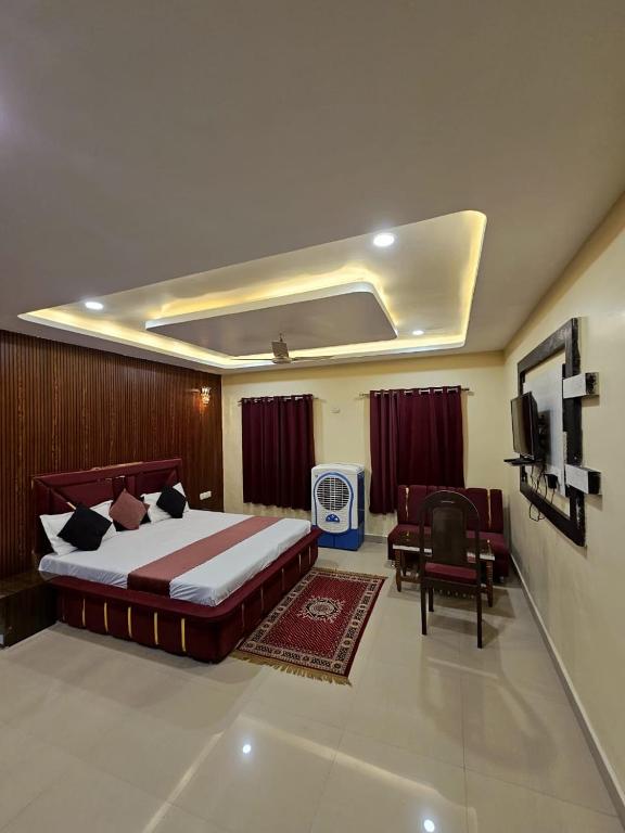 a bedroom with a bed and a couch and a tv at VR Palace in Kānpur