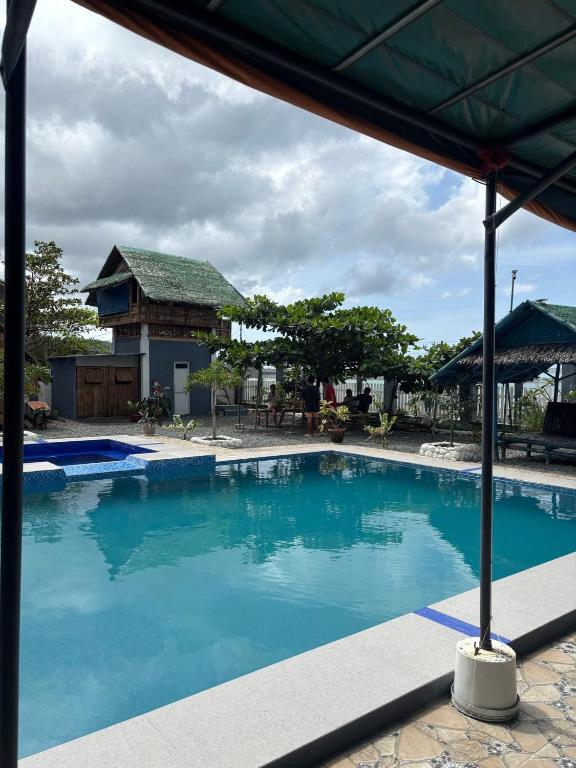 a large blue swimming pool with a house in the background at Brandons Beach Resort in Inayauan