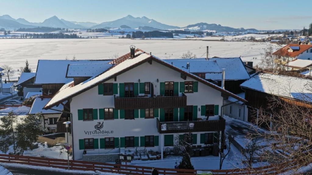 a white building with snow on the roof at Vitusfort Urlaub im Allgäu - Ferienwohnungen & Themenzimmer in Hopfen am See in Füssen