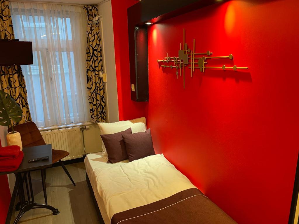 a red room with a bed and a red wall at Hotel Anco in Ons Belang