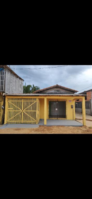 a yellow house with a fence in front of it at AjuruLima in Bragança