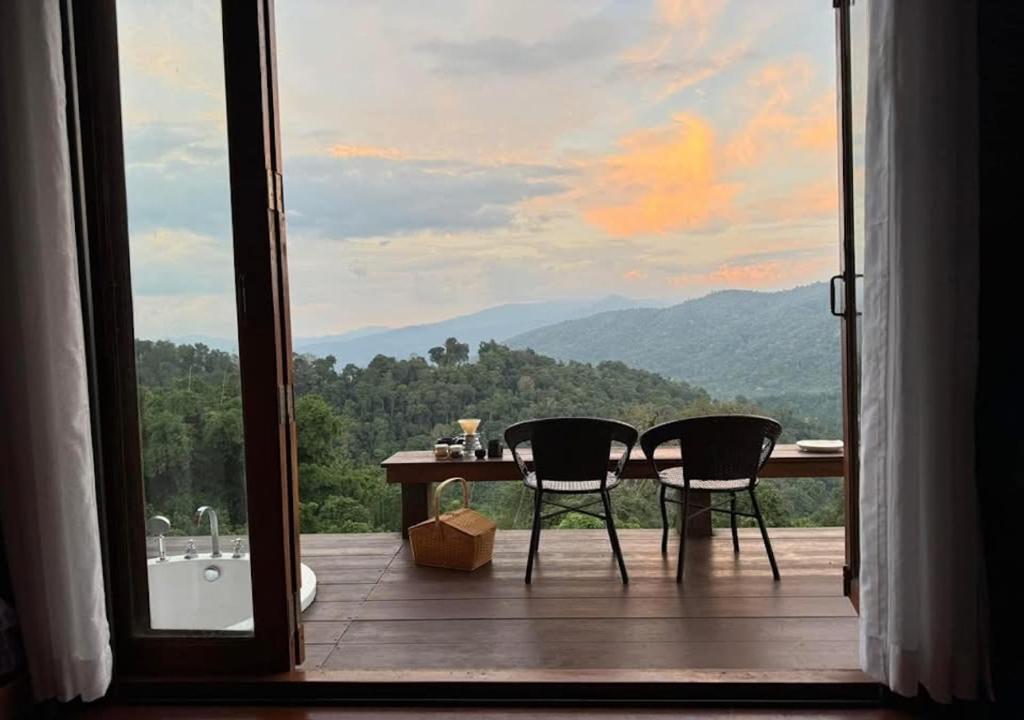 a bathroom with a table and two chairs and a tub at Thammachart The Nature in Ban Kai Noi