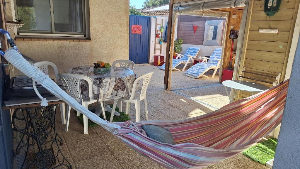 a hammock on a patio with a table and chairs at Cosy kaz in Bormes-les-Mimosas