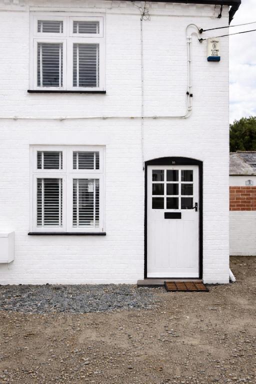 a white house with a white door and two windows at Corner Cottage in Derby