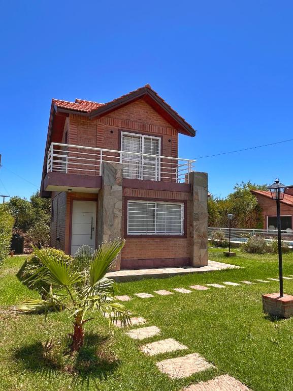 a red brick house with a palm tree in the yard at Cabañas Abril in Merlo