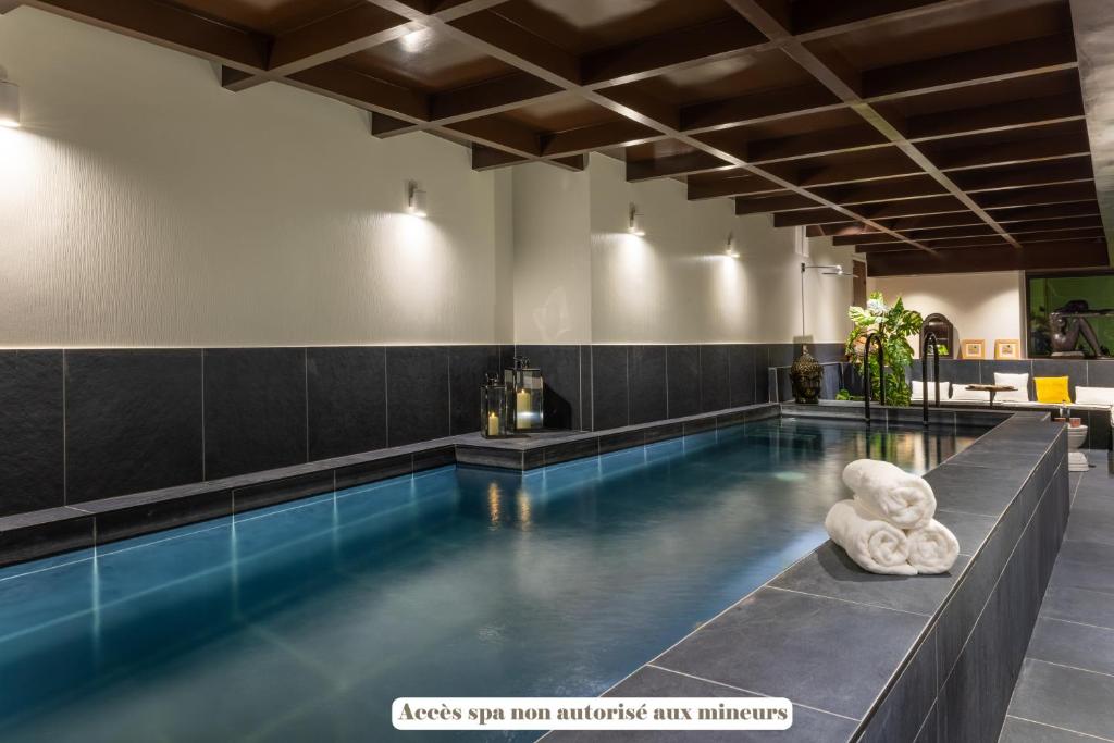 a pool in a building with a tiled floor at Hôtel & SPA Le Chêne Vert in Brive-la-Gaillarde