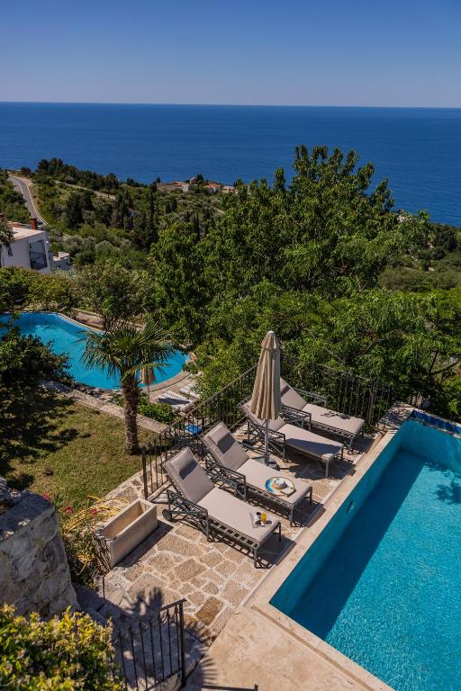 an outdoor swimming pool with lounge chairs and an umbrella at Castello degli Aranci Eco Resort in Reževići
