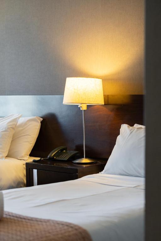 a lamp on a night stand next to two beds at Hotel Crans Montana in San Carlos de Bariloche