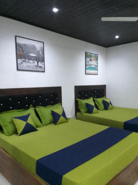 two beds in a room with green and blue at Moonlight Resort in Anuradhapura