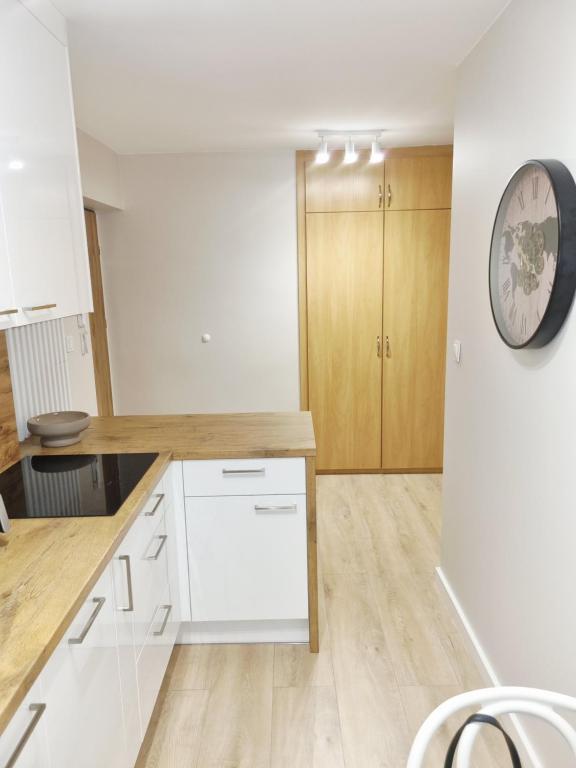 a kitchen with white cabinets and a clock on the wall at Apartament Sobótka in Sobótka