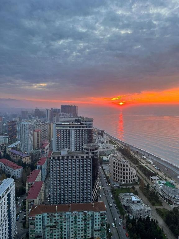 a view of a city with a sunset over the ocean at ASKO aprtament beach batumi in Batumi