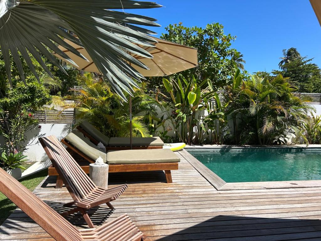 a swimming pool with two chairs and an umbrella next to a pool at La belle de jour in Fortim