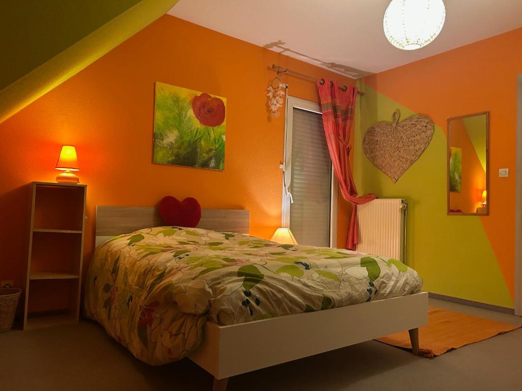 a bedroom with a bed and an orange wall at Chez Corinne et Michel in Saasenheim