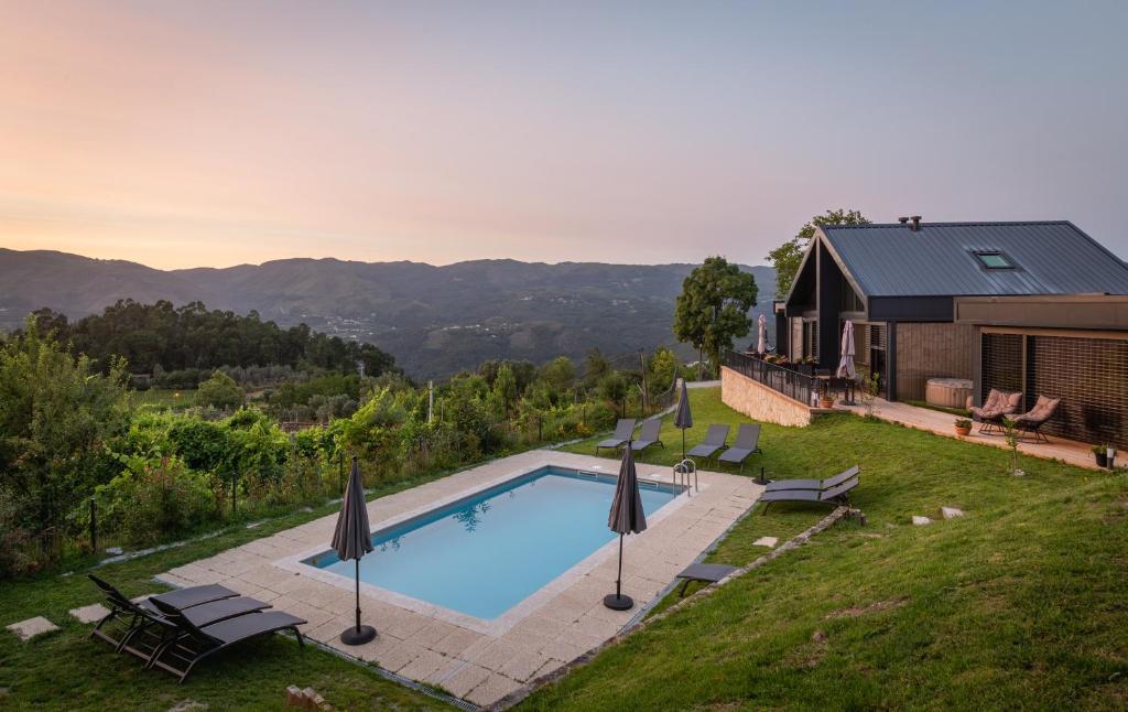 a swimming pool with umbrellas and a house at Casas Bouro 1 Casa Das Hortências in Terras de Bouro