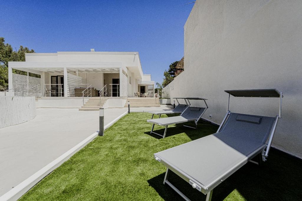a white house with chairs on the lawn at Holiday burrone in Favignana